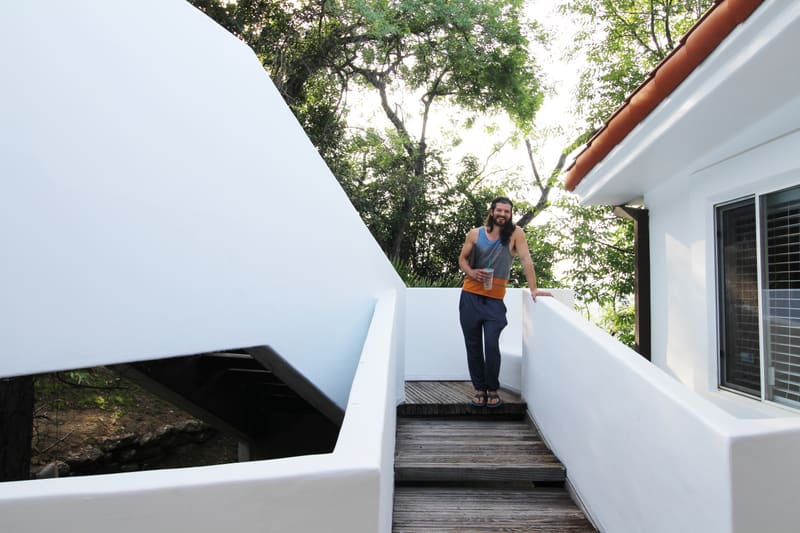 Person standing on white outdoor stairs of a modern white house surrounded by trees