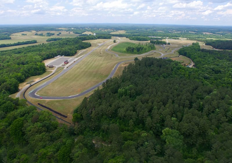 Aerial view of a road-racing circuit winding through green forest and fields