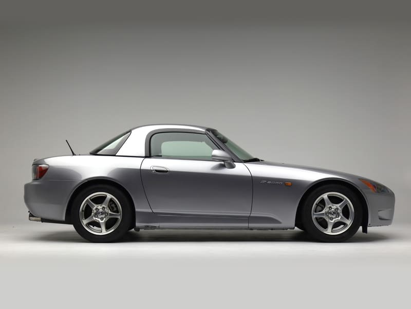 Silver Honda S2000 with hardtop, side profile on a gray studio backdrop