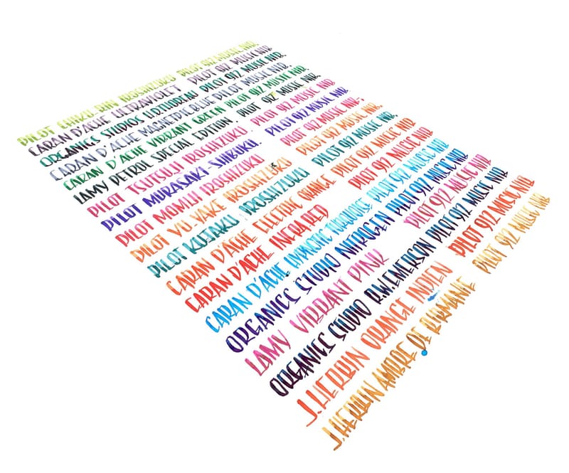 Sheet of hand-lettered ink swatches in rainbow colors, each line naming the ink and Pilot 912 music nib, photographed at an angle on white