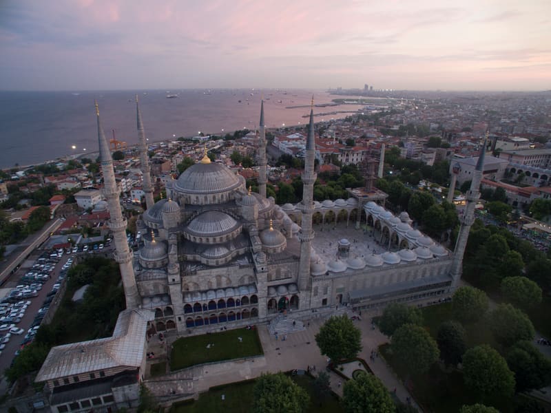 Aerial view of the Blue Mosque and its minarets at sunset, with the sea and city beyond
