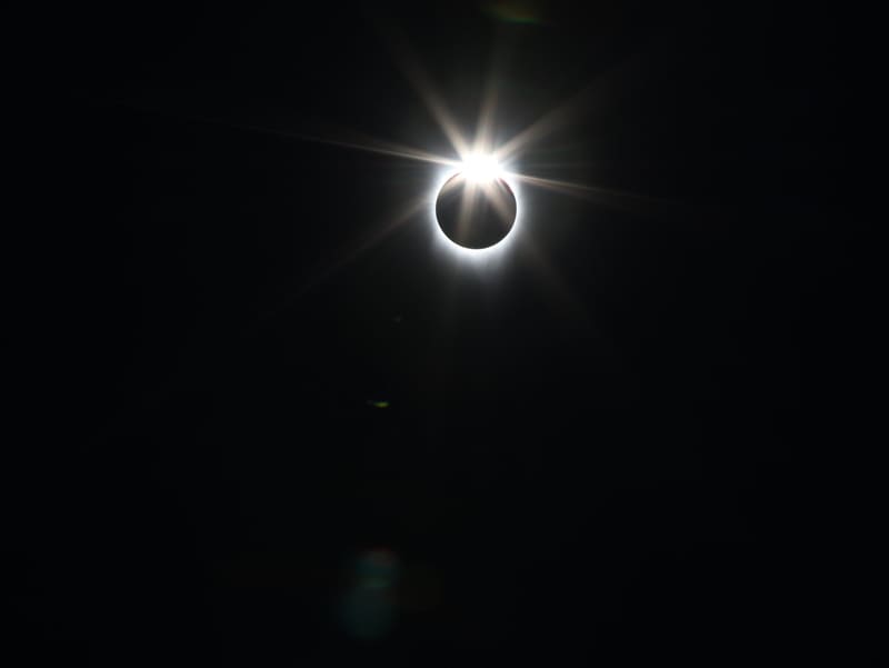 Total solar eclipse at the diamond ring moment, a bright starburst at the edge of the dark moon